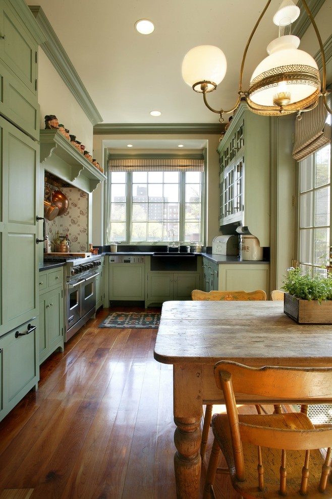 Exempel på ett mellanstort lantligt u-kök, med en rustik diskho, luckor med upphöjd panel, gröna skåp, bänkskiva i täljsten, svart stänkskydd, stänkskydd i sten, integrerade vitvaror och mellanmörkt trägolv