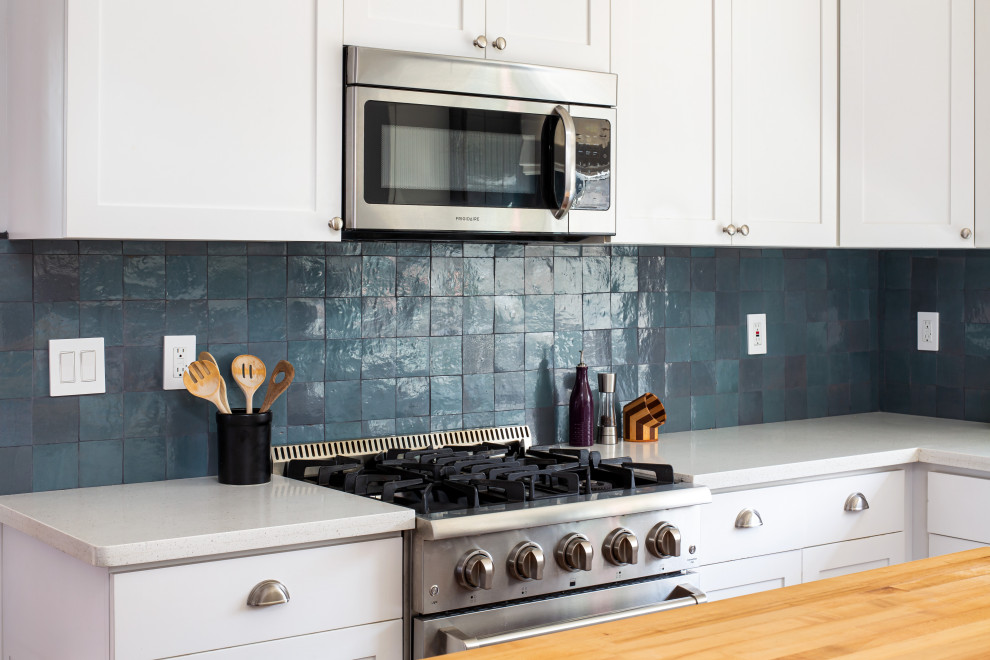 Exempel på ett mellanstort klassiskt vit vitt kök, med en nedsänkt diskho, skåp i shakerstil, vita skåp, bänkskiva i akrylsten, blått stänkskydd, stänkskydd i keramik, rostfria vitvaror, mörkt trägolv, en köksö och brunt golv