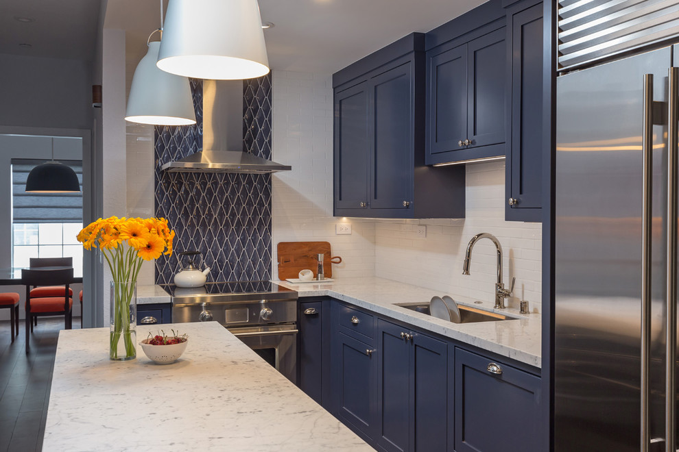 Foto på ett litet vintage vit kök, med en undermonterad diskho, skåp i shakerstil, blå skåp, marmorbänkskiva, blått stänkskydd, stänkskydd i keramik, rostfria vitvaror, mellanmörkt trägolv, en köksö och brunt golv