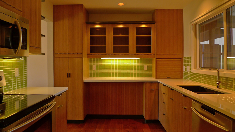 デンバーにある高級な中くらいなモダンスタイルのおしゃれなキッチン (アンダーカウンターシンク、フラットパネル扉のキャビネット、中間色木目調キャビネット、クオーツストーンカウンター、緑のキッチンパネル、セラミックタイルのキッチンパネル、シルバーの調理設備、無垢フローリング、白いキッチンカウンター) の写真