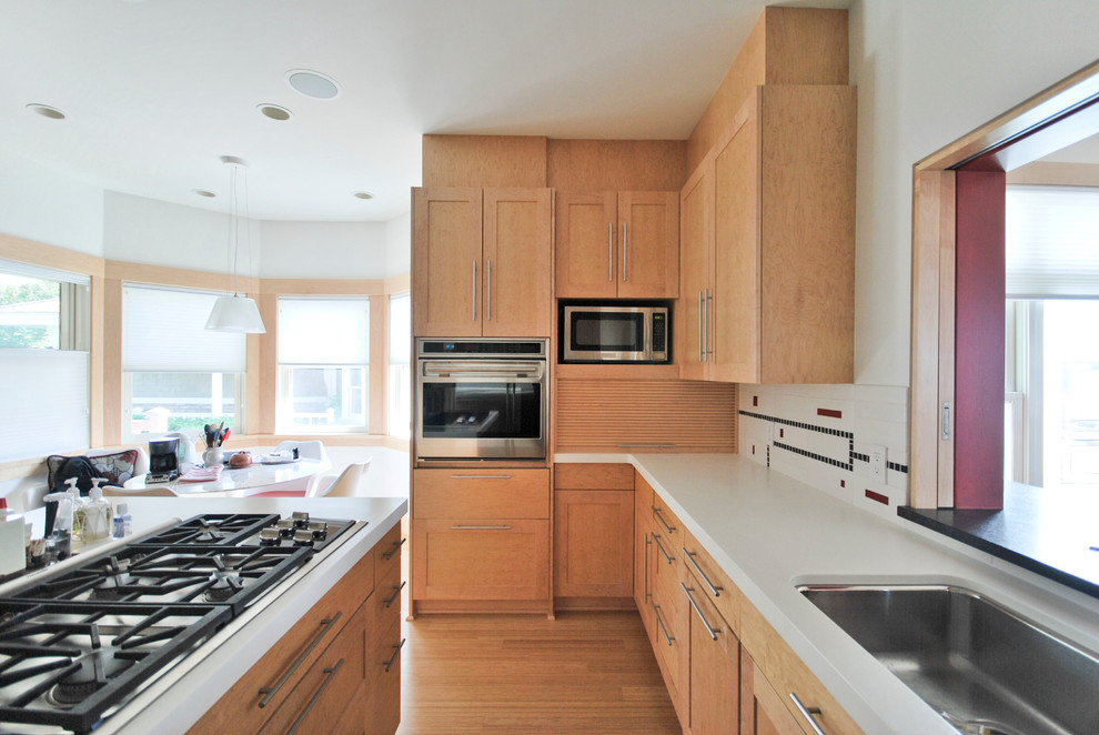 Example of a large transitional u-shaped bamboo floor enclosed kitchen design in Minneapolis with a double-bowl sink, shaker cabinets, light wood cabinets, quartz countertops, multicolored backsplash, ceramic backsplash, stainless steel appliances and an island