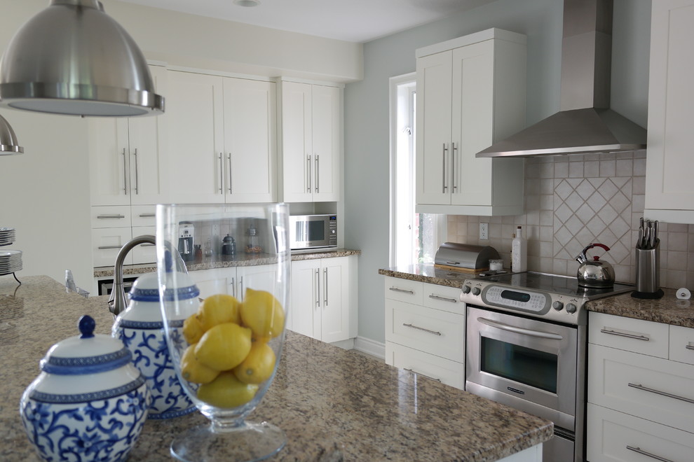 Example of a mid-sized cottage chic l-shaped ceramic tile eat-in kitchen design in Toronto with a drop-in sink, shaker cabinets, white cabinets, granite countertops, beige backsplash, ceramic backsplash, stainless steel appliances and an island