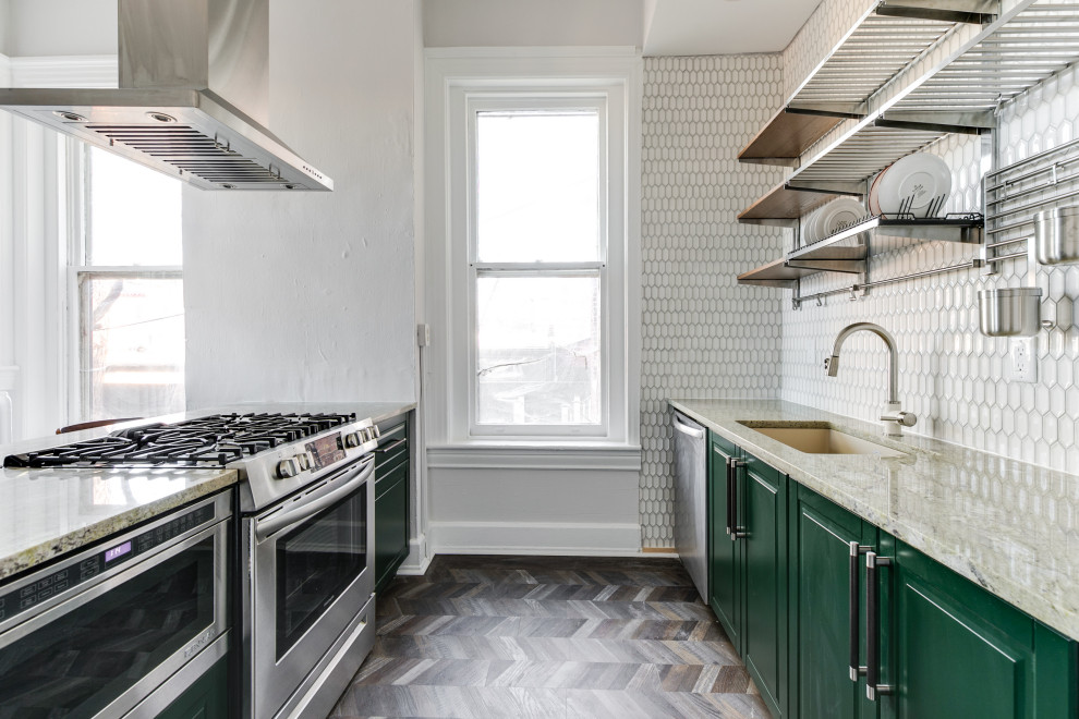 Modern inredning av ett mellanstort grön grönt kök, med en enkel diskho, luckor med upphöjd panel, gröna skåp, granitbänkskiva, vitt stänkskydd, stänkskydd i keramik, rostfria vitvaror, laminatgolv och en halv köksö