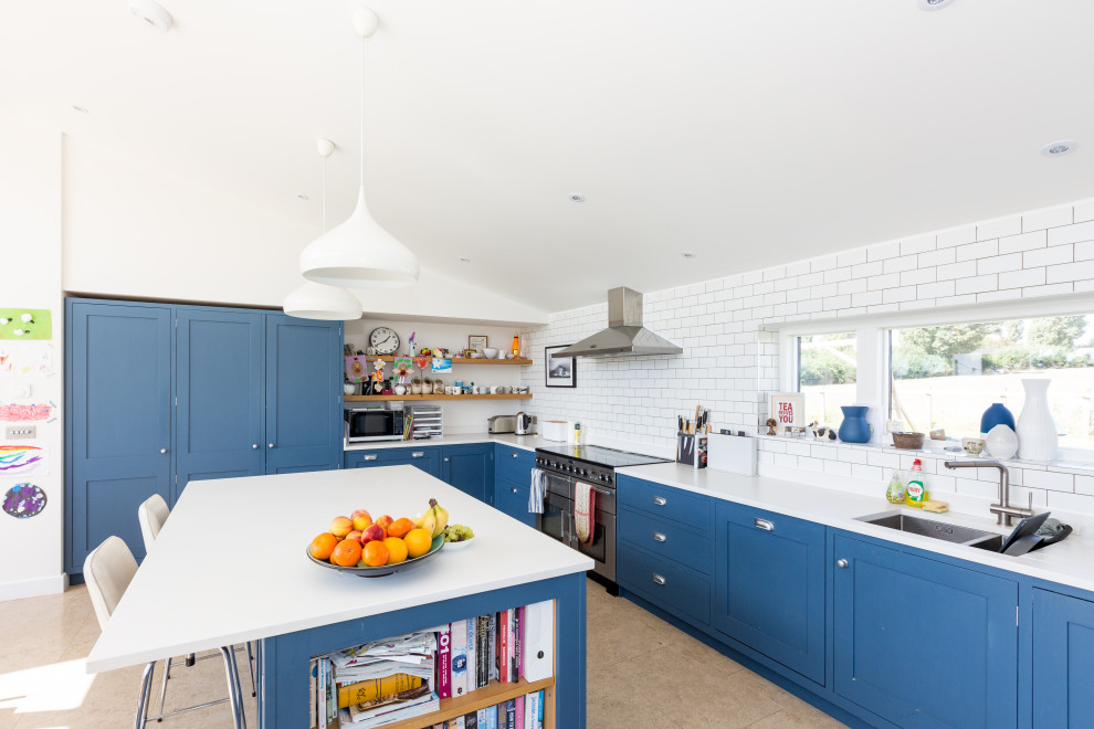 Inspiration for a large classic l-shaped kitchen in Other with a double-bowl sink, shaker cabinets, blue cabinets, white splashback, metro tiled splashback, stainless steel appliances, porcelain flooring, an island, beige floors and white worktops.