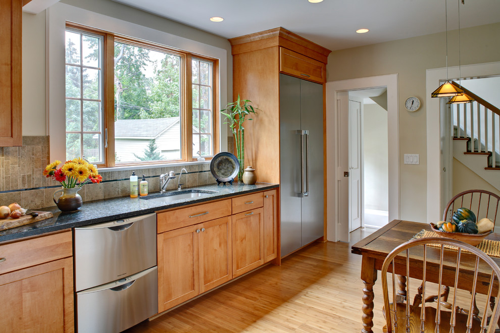 Inspiration for a timeless l-shaped eat-in kitchen remodel in Newark with stainless steel appliances, an undermount sink, shaker cabinets, medium tone wood cabinets, granite countertops, multicolored backsplash and porcelain backsplash