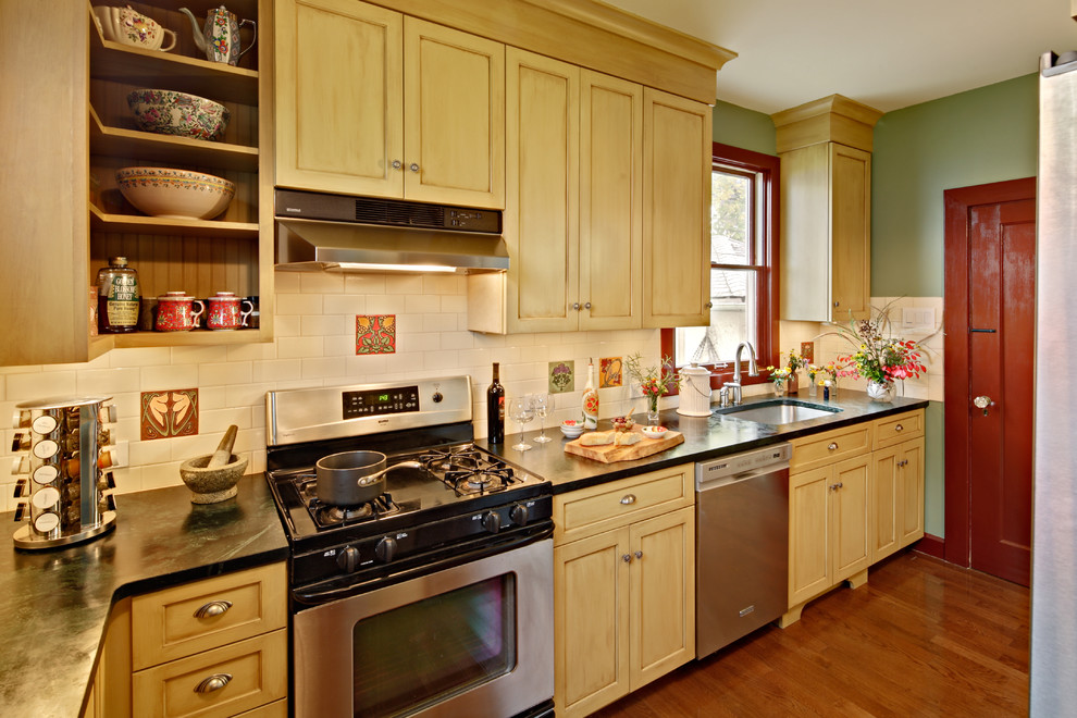 Geschlossene Urige Küche in U-Form mit Unterbauwaschbecken, Schrankfronten im Shaker-Stil, gelben Schränken, Speckstein-Arbeitsplatte, Küchenrückwand in Weiß, Rückwand aus Keramikfliesen und Küchengeräten aus Edelstahl in New York