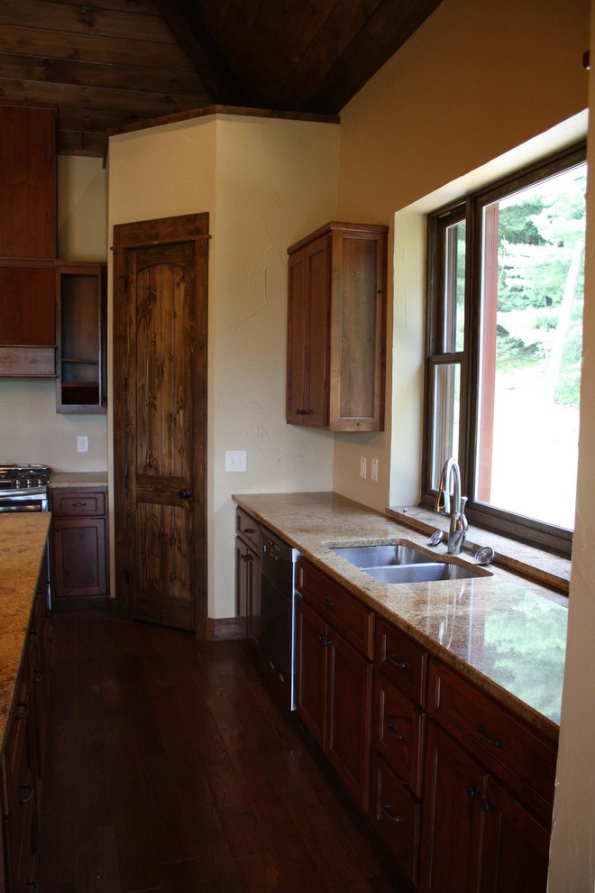 Esempio di una cucina moderna con lavello sottopiano, ante con riquadro incassato, ante in legno bruno, top in granito, elettrodomestici in acciaio inossidabile e parquet scuro