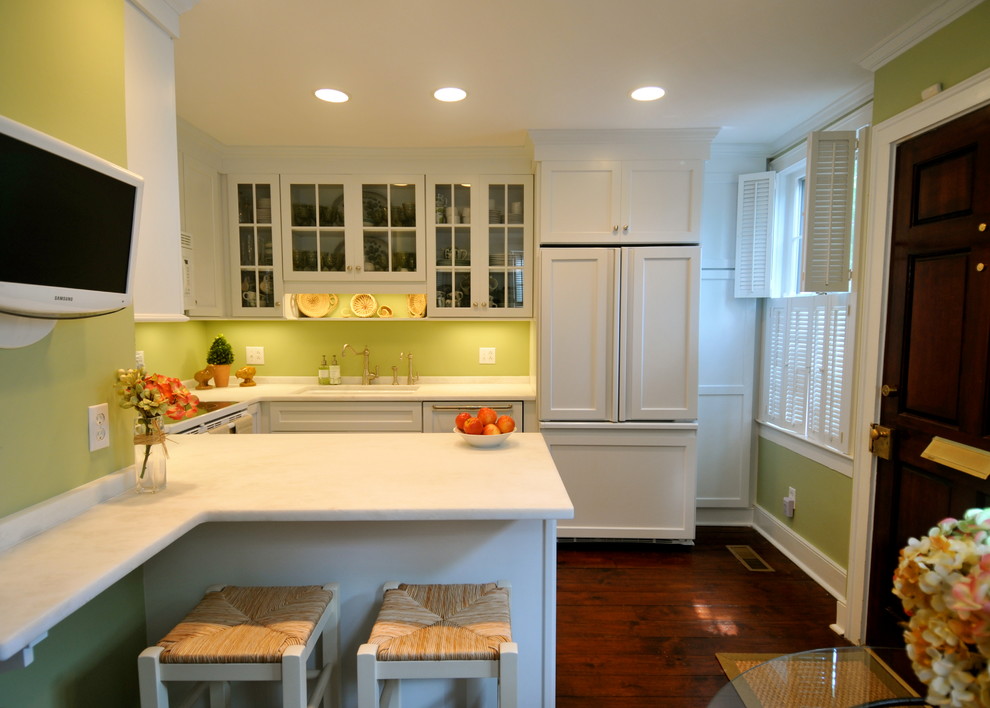 Small country u-shaped kitchen/diner in Charleston with a submerged sink, glass-front cabinets, white cabinets, marble worktops, green splashback, white appliances, dark hardwood flooring and a breakfast bar.