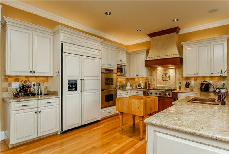Foto di una cucina classica di medie dimensioni con ante in stile shaker, ante bianche, top in granito, paraspruzzi beige, elettrodomestici in acciaio inossidabile e pavimento in legno massello medio