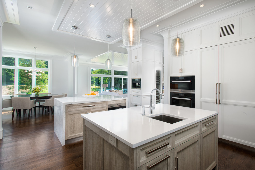 Inspiration for a large transitional dark wood floor and brown floor open concept kitchen remodel in New York with an undermount sink, recessed-panel cabinets, distressed cabinets, quartz countertops, white backsplash, mosaic tile backsplash, black appliances, two islands and white countertops