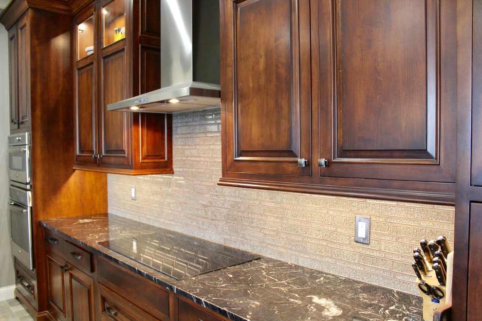 Example of a large arts and crafts u-shaped ceramic tile and beige floor eat-in kitchen design in St Louis with dark wood cabinets, stainless steel appliances, an island, a drop-in sink, raised-panel cabinets, granite countertops, beige backsplash and ceramic backsplash