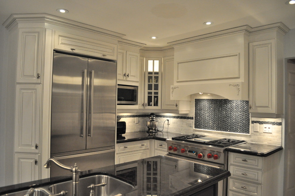 Klassische Küche in L-Form mit Doppelwaschbecken, profilierten Schrankfronten, weißen Schränken, Küchenrückwand in Weiß und Küchengeräten aus Edelstahl in Toronto