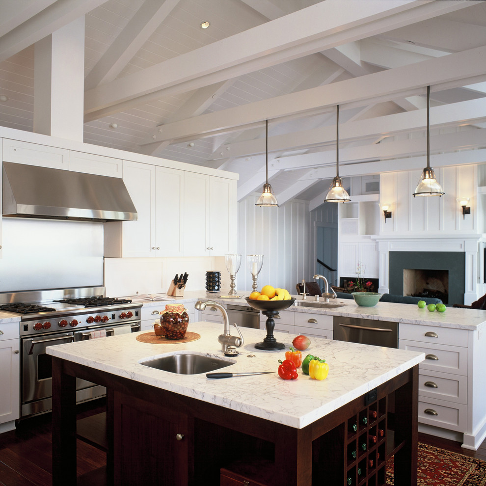 Bild på ett stort maritimt kök med öppen planlösning, med rostfria vitvaror, marmorbänkskiva, en undermonterad diskho, luckor med infälld panel, vita skåp, vitt stänkskydd, stänkskydd i trä, mellanmörkt trägolv och en köksö