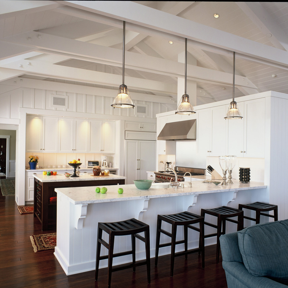 Exempel på ett stort maritimt kök med öppen planlösning, med integrerade vitvaror, marmorbänkskiva, en undermonterad diskho, vita skåp, vitt stänkskydd, mörkt trägolv, en köksö, skåp i shakerstil och stänkskydd i trä