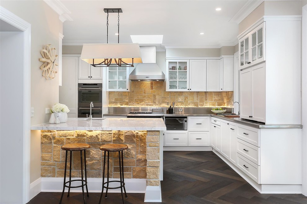 Exempel på ett lantligt kök, med en undermonterad diskho, luckor med infälld panel, vita skåp, marmorbänkskiva, rostfria vitvaror, mörkt trägolv, en köksö och brunt golv