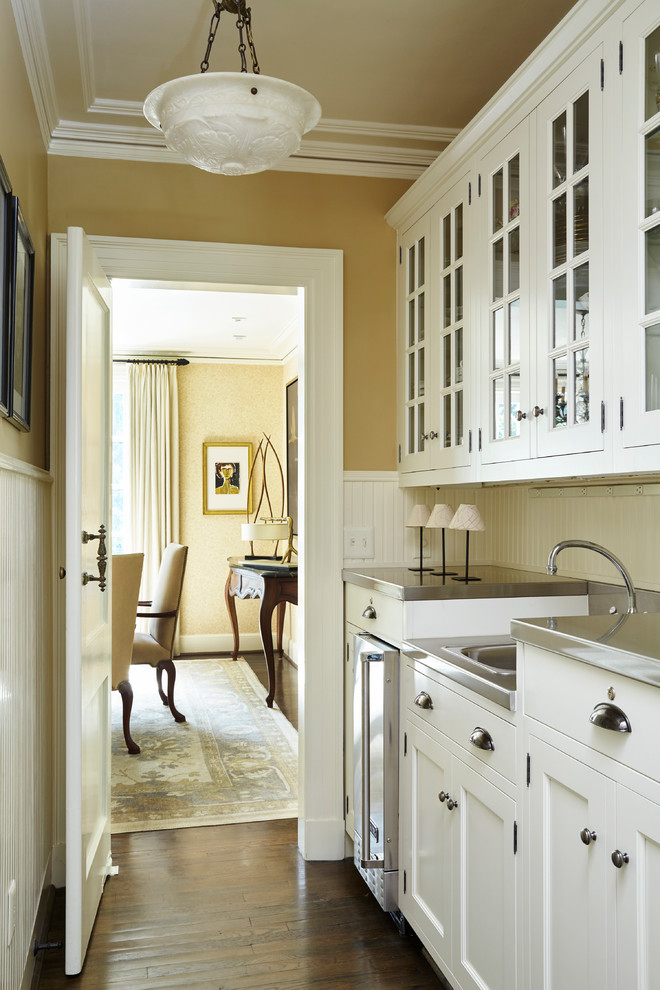 Klassische Küche mit Vorratsschrank, integriertem Waschbecken, Schrankfronten im Shaker-Stil, weißen Schränken, Edelstahl-Arbeitsplatte, Küchenrückwand in Weiß, Küchengeräten aus Edelstahl und dunklem Holzboden in Atlanta