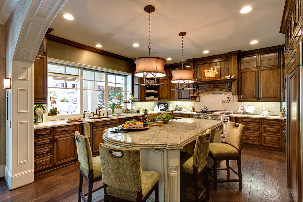 Inspiration for a large traditional u-shaped kitchen/diner in Orange County with a submerged sink, raised-panel cabinets, medium wood cabinets, beige splashback, stainless steel appliances, granite worktops, dark hardwood flooring, an island and brown floors.