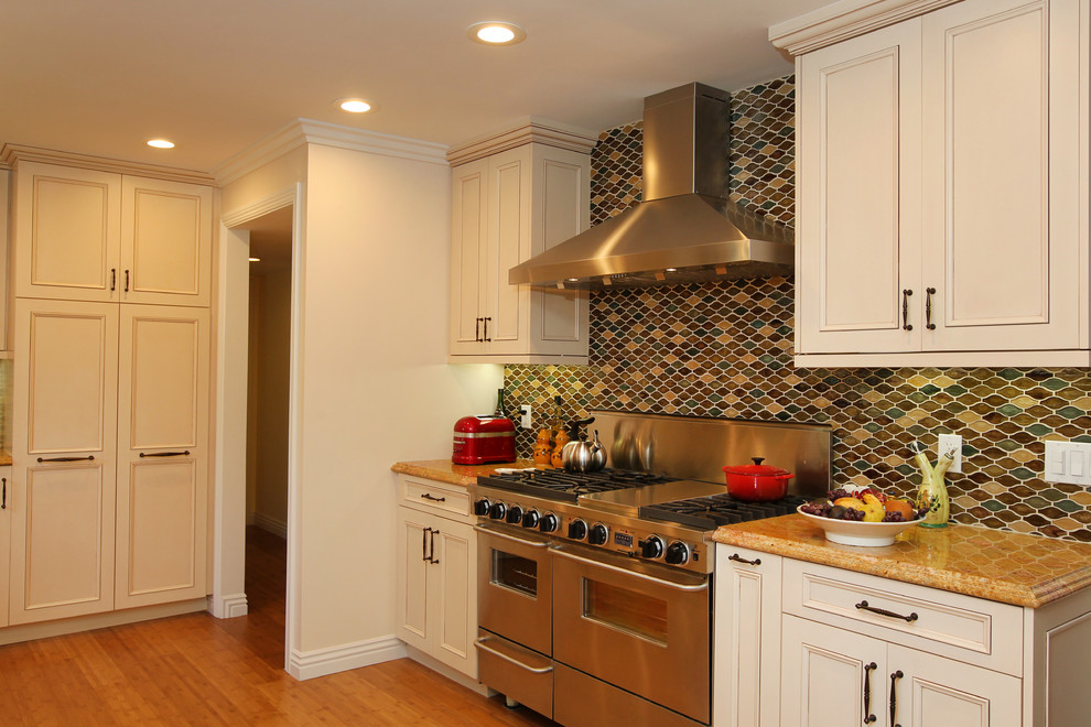 Exempel på ett mellanstort klassiskt kök, med en undermonterad diskho, luckor med infälld panel, beige skåp, granitbänkskiva, flerfärgad stänkskydd, stänkskydd i glaskakel, rostfria vitvaror, bambugolv och beiget golv