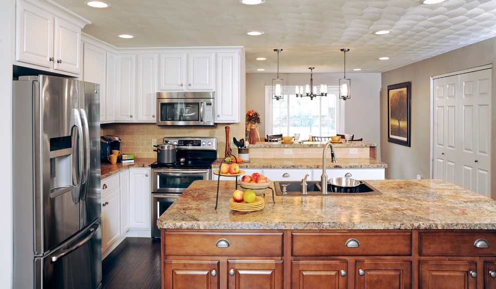 Exempel på ett stort klassiskt kök, med en dubbel diskho, luckor med upphöjd panel, vita skåp, granitbänkskiva, beige stänkskydd, stänkskydd i stenkakel, rostfria vitvaror, mörkt trägolv och en köksö