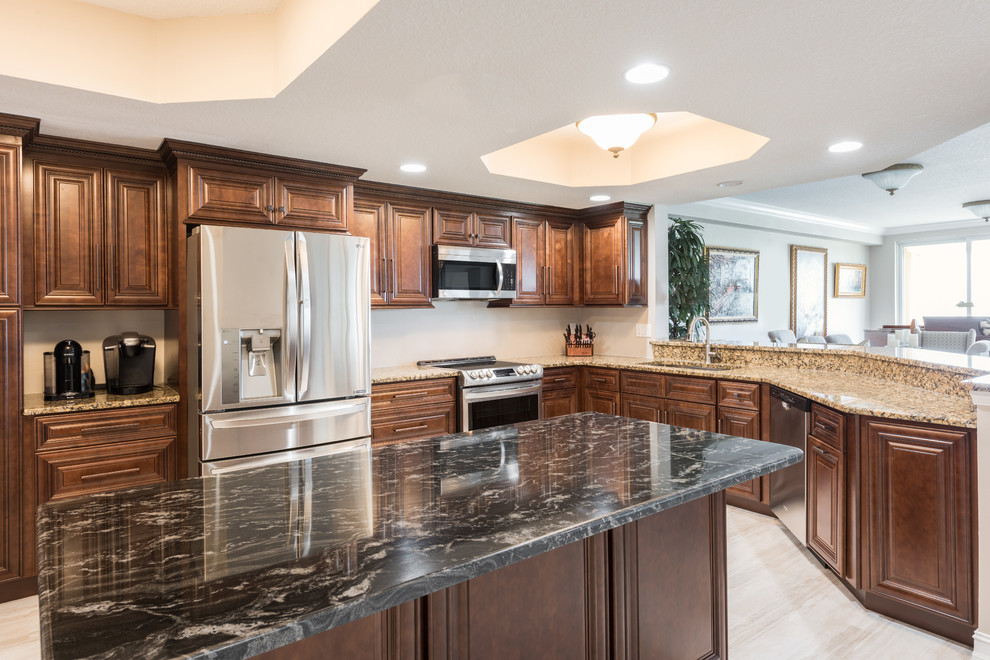 Photo of a large classic l-shaped open plan kitchen in Orlando with a submerged sink, raised-panel cabinets, medium wood cabinets, granite worktops, stainless steel appliances, vinyl flooring, an island, beige floors and beige worktops.