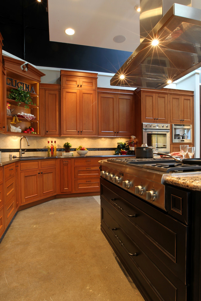 Klassisk inredning av ett mycket stort kök, med en undermonterad diskho, luckor med profilerade fronter, skåp i mellenmörkt trä, granitbänkskiva, beige stänkskydd, stänkskydd i travertin, rostfria vitvaror, betonggolv, en köksö och grått golv