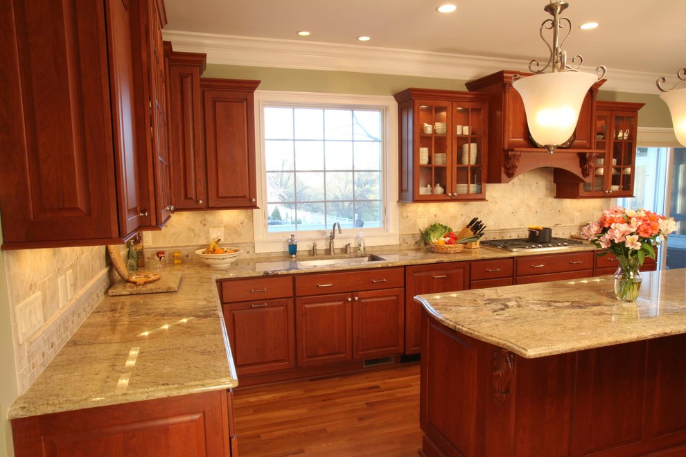 Eat-in kitchen - large traditional u-shaped medium tone wood floor eat-in kitchen idea in New York with an undermount sink, raised-panel cabinets, medium tone wood cabinets, granite countertops, beige backsplash, ceramic backsplash, stainless steel appliances and an island