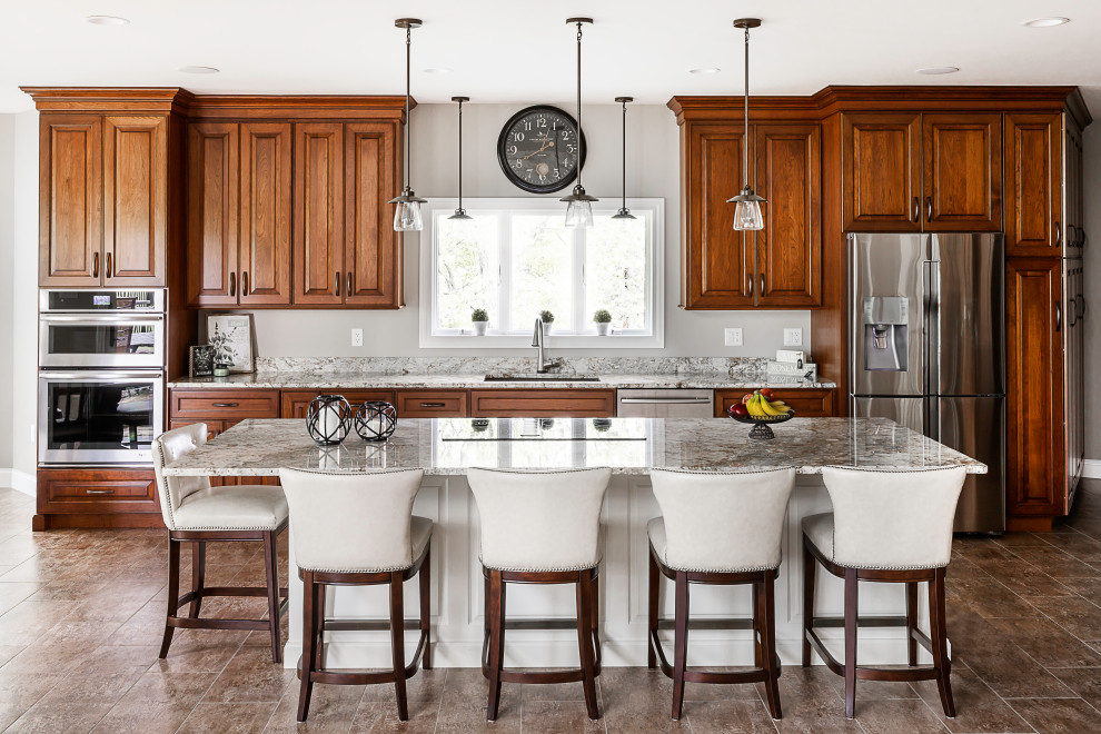 Example of a large classic galley vinyl floor and brown floor kitchen design in Other with an undermount sink, raised-panel cabinets, dark wood cabinets, granite countertops, stainless steel appliances, an island and gray countertops