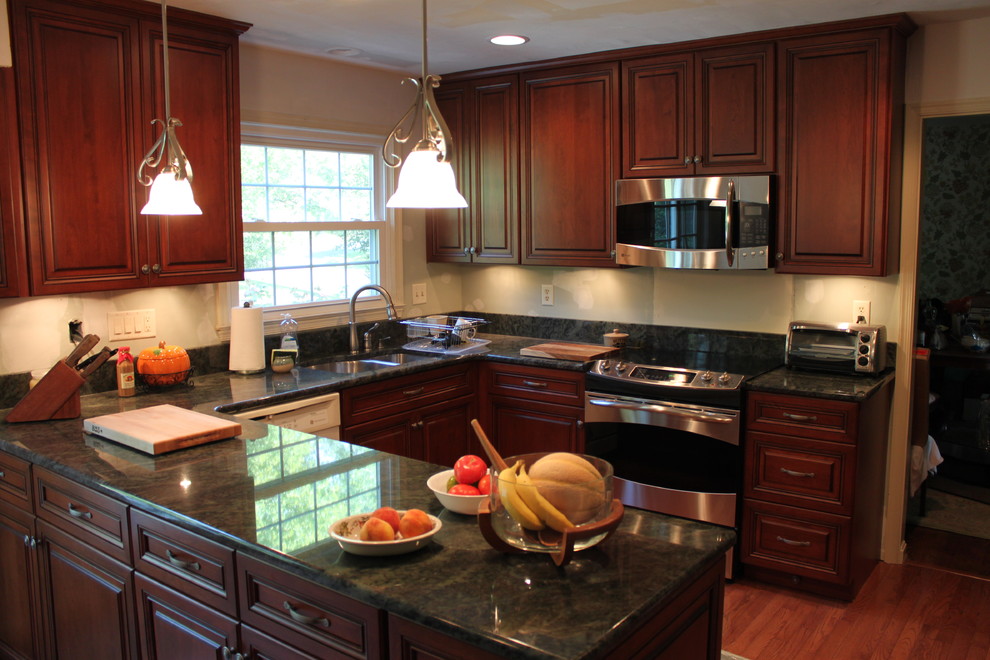 Inspiration for a large timeless u-shaped medium tone wood floor enclosed kitchen remodel in Baltimore with a double-bowl sink, raised-panel cabinets, medium tone wood cabinets, granite countertops, beige backsplash, stainless steel appliances and a peninsula