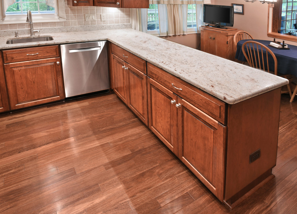 Exempel på ett avskilt, mellanstort klassiskt beige beige u-kök, med en undermonterad diskho, luckor med upphöjd panel, skåp i mörkt trä, granitbänkskiva, beige stänkskydd, stänkskydd i keramik, rostfria vitvaror, mellanmörkt trägolv och brunt golv