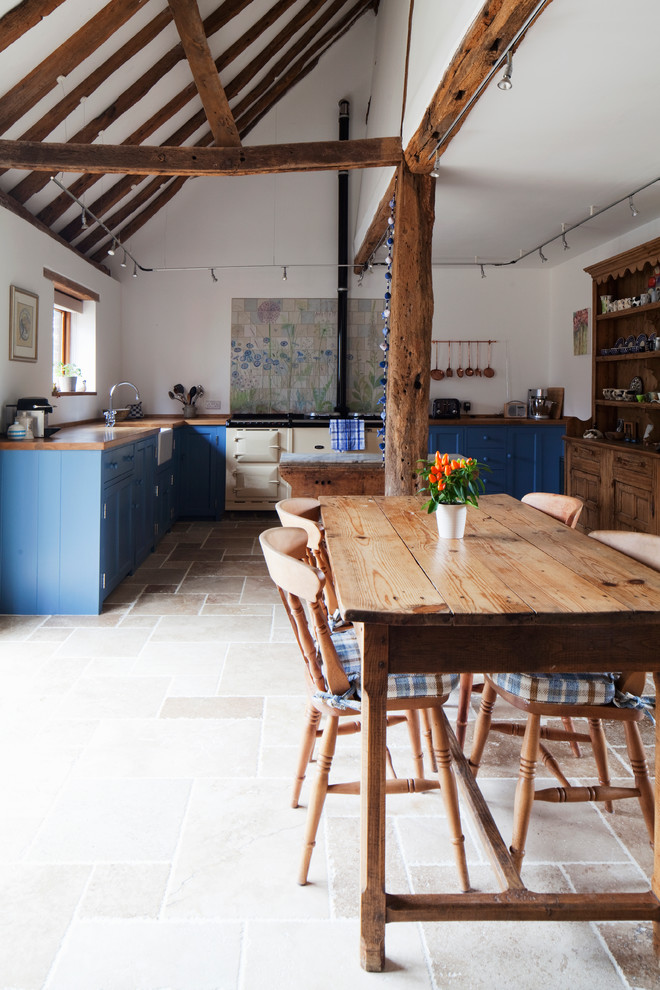 Идея дизайна: угловая кухня в стиле кантри с обеденным столом, с полувстраиваемой мойкой (с передним бортиком), синими фасадами и деревянной столешницей