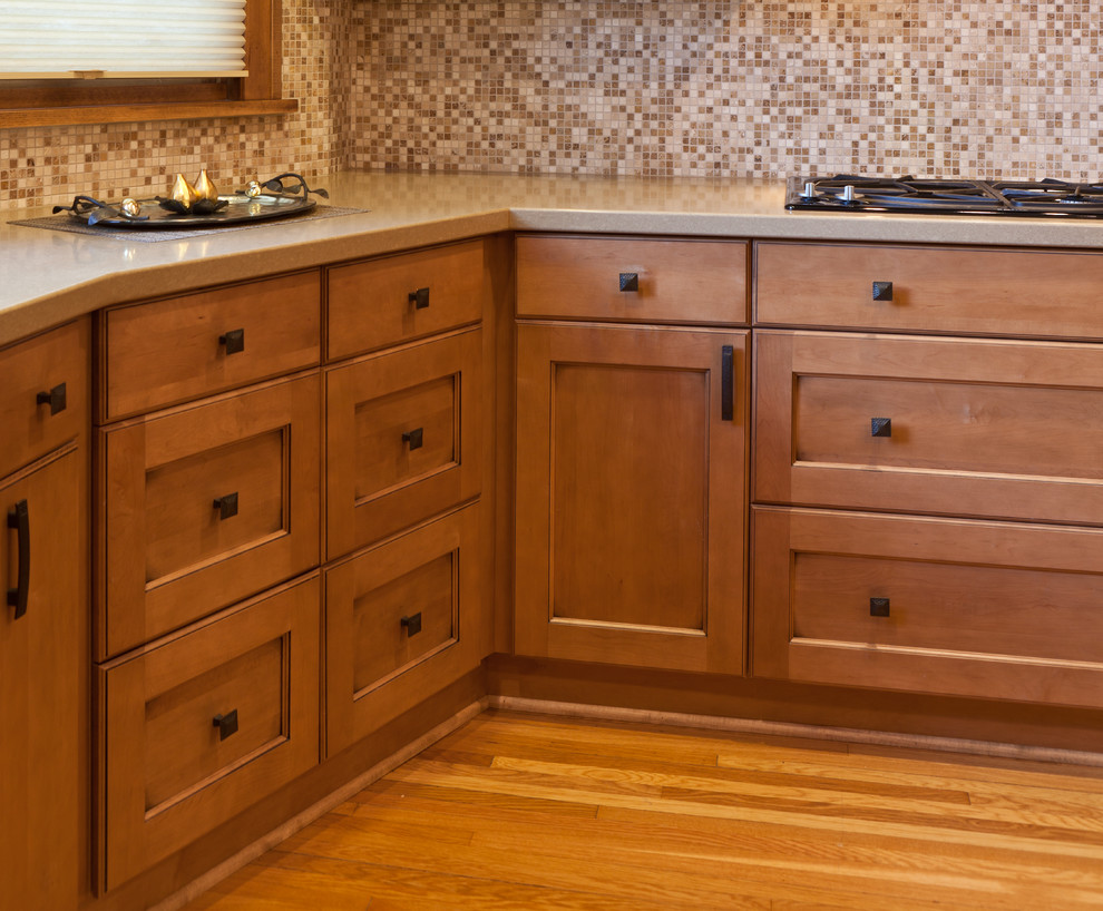Aménagement d'une cuisine classique en bois brun avec un plan de travail en quartz modifié, une crédence marron, une crédence en céramique, un électroménager en acier inoxydable et parquet clair.