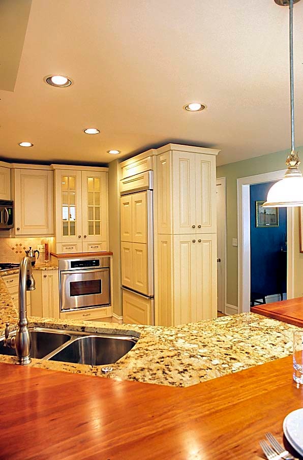 Exempel på ett mellanstort klassiskt kök, med en dubbel diskho, luckor med upphöjd panel, beige skåp, granitbänkskiva, beige stänkskydd, stänkskydd i keramik, rostfria vitvaror, mellanmörkt trägolv och en halv köksö