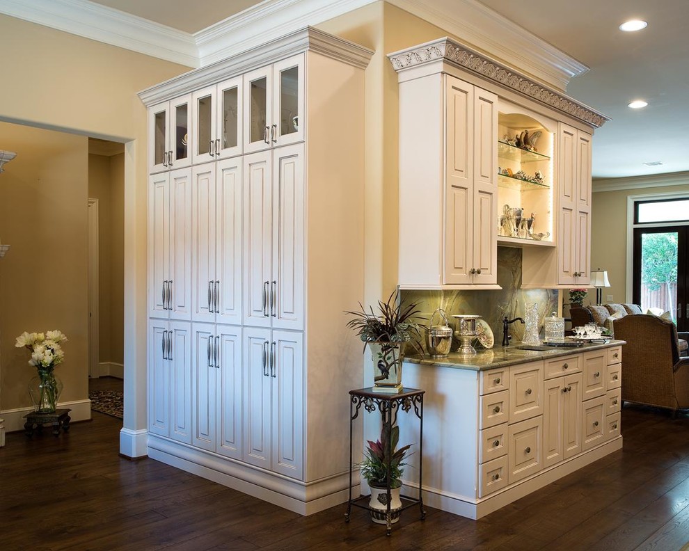 Exempel på ett stort klassiskt kök, med luckor med upphöjd panel, vita skåp, integrerade vitvaror, en köksö, en undermonterad diskho, granitbänkskiva, grönt stänkskydd, stänkskydd i sten, mörkt trägolv och brunt golv