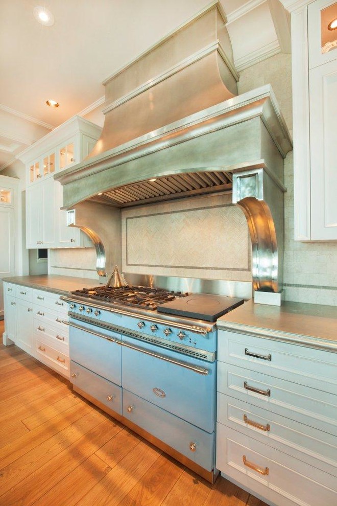 Klassisk inredning av ett stort kök, med vita skåp, färgglada vitvaror, ljust trägolv, en köksö och brunt golv