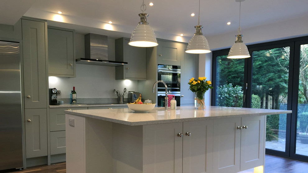 Example of a mid-sized classic single-wall eat-in kitchen design in London with a farmhouse sink, shaker cabinets, granite countertops, stainless steel appliances, an island and beige countertops