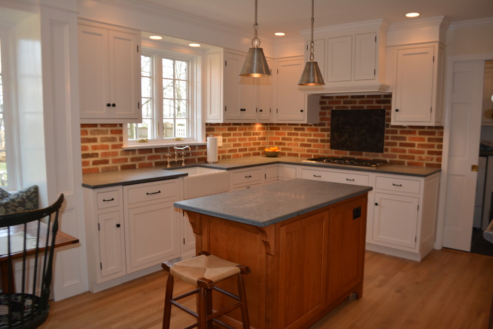 Inspiration for a small country u-shaped medium tone wood floor and brown floor eat-in kitchen remodel in Philadelphia with a farmhouse sink, white cabinets, soapstone countertops and an island