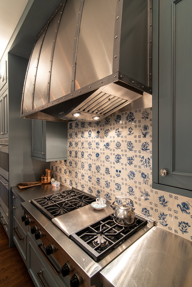 Bild på ett avskilt, mellanstort vintage l-kök, med luckor med profilerade fronter, grå skåp, stänkskydd i keramik, integrerade vitvaror, mellanmörkt trägolv, brunt golv, bänkskiva i rostfritt stål och blått stänkskydd