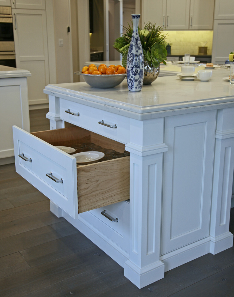 Inspiration for a large timeless l-shaped medium tone wood floor and gray floor eat-in kitchen remodel in Milwaukee with a farmhouse sink, shaker cabinets, white cabinets, quartz countertops, white backsplash, marble backsplash, stainless steel appliances and two islands