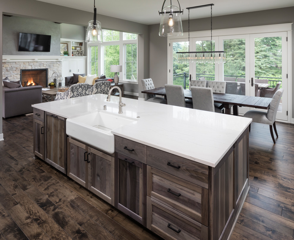 Photo of a large classic l-shaped kitchen/diner in Minneapolis with an island, recessed-panel cabinets, white cabinets, engineered stone countertops, white splashback, ceramic splashback, a belfast sink, stainless steel appliances, dark hardwood flooring and brown floors.