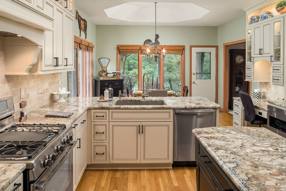 Design ideas for a large classic u-shaped kitchen/diner in Columbus with a submerged sink, beaded cabinets, beige cabinets, engineered stone countertops, beige splashback, travertine splashback, stainless steel appliances, light hardwood flooring, an island, brown floors and beige worktops.