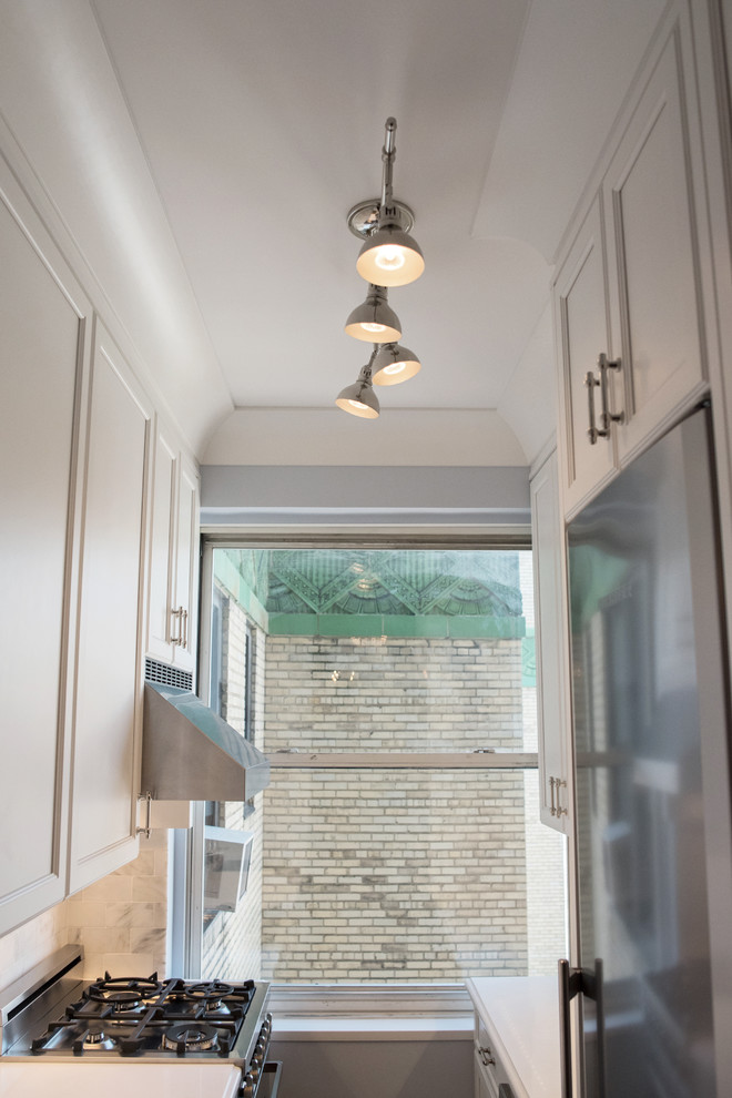 Photo of a small traditional galley enclosed kitchen in New York with a single-bowl sink, white cabinets, quartz worktops, white splashback, stone tiled splashback, stainless steel appliances, porcelain flooring, no island and recessed-panel cabinets.