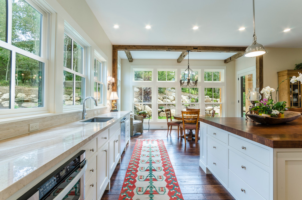 Bild på ett stort vintage kök, med en undermonterad diskho, luckor med profilerade fronter, vita skåp, marmorbänkskiva, beige stänkskydd, stänkskydd i stenkakel, rostfria vitvaror, mörkt trägolv och en köksö