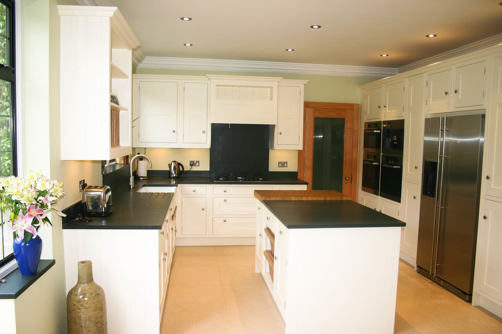 Mittelgroße Klassische Küche in U-Form mit Landhausspüle, Schrankfronten im Shaker-Stil, weißen Schränken, Granit-Arbeitsplatte, Küchengeräten aus Edelstahl und Kücheninsel in Surrey