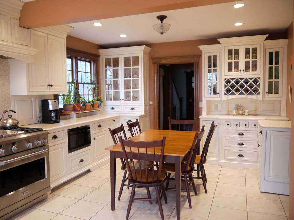 Klassisk inredning av ett kök och matrum, med luckor med upphöjd panel, vita skåp, vitt stänkskydd och rostfria vitvaror