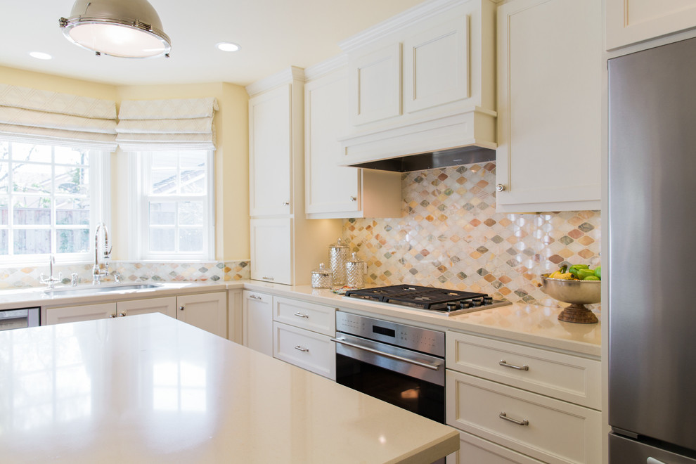 Klassisk inredning av ett mellanstort l-kök, med en undermonterad diskho, skåp i shakerstil, vita skåp, bänkskiva i kvarts, flerfärgad stänkskydd, stänkskydd i stenkakel, rostfria vitvaror, mellanmörkt trägolv och en köksö