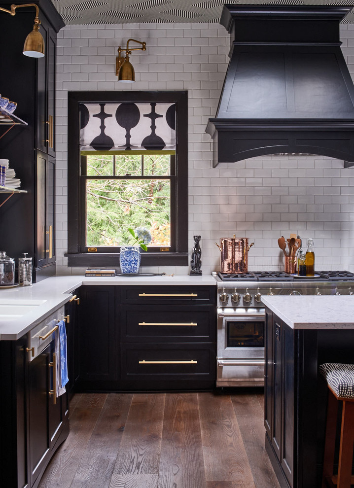 Mid-sized transitional l-shaped medium tone wood floor and brown floor kitchen photo in Raleigh with shaker cabinets, white backsplash, subway tile backsplash, stainless steel appliances, an island, an undermount sink and quartz countertops