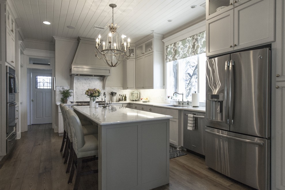 Mid-sized elegant u-shaped medium tone wood floor enclosed kitchen photo in Miami with a double-bowl sink, raised-panel cabinets, gray cabinets, quartz countertops, gray backsplash, porcelain backsplash, stainless steel appliances and an island