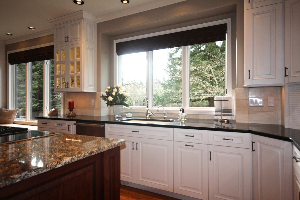 Example of a large classic u-shaped medium tone wood floor eat-in kitchen design in Seattle with a drop-in sink, beaded inset cabinets, white cabinets, granite countertops, beige backsplash, stone tile backsplash and black appliances