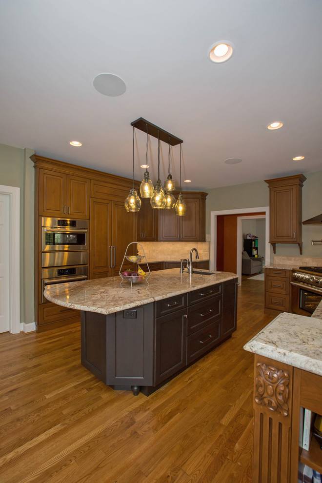 Example of a large classic u-shaped medium tone wood floor and brown floor open concept kitchen design in Cincinnati with an undermount sink, raised-panel cabinets, medium tone wood cabinets, marble countertops, beige backsplash, ceramic backsplash, stainless steel appliances and an island
