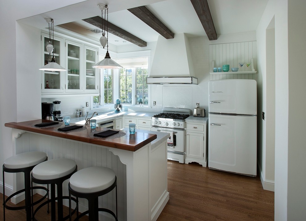 Стильный дизайн: п-образная кухня в классическом стиле с фасадами в стиле шейкер, белыми фасадами, деревянной столешницей, белым фартуком и белой техникой - последний тренд